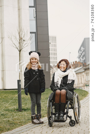 Mother in a wheelchair with hre daughter Mother in a wheelchair with hre daughter 74108360