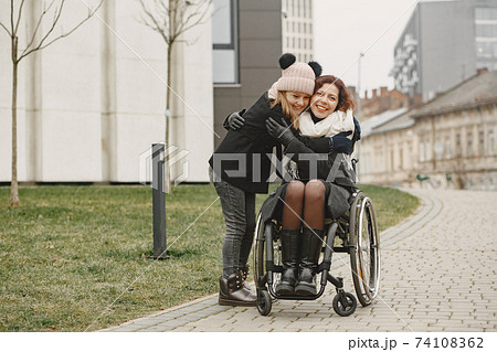 Mother in a wheelchair with hre daughter 74108362