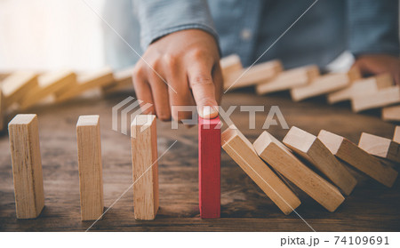 close-up hand The hand of a businessman who is stopping or preventing a falling block.Risk protection concept,Eliminating the risk 74109691