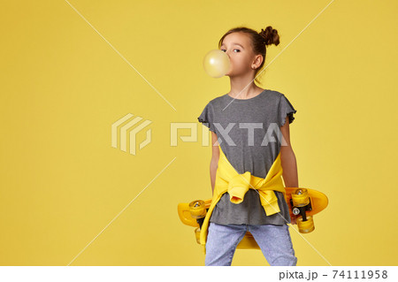 child girl with skateboard blowing a big bubble gum 74111958