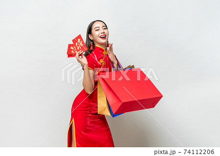 Portrait of Asian woman in traditional dress holding bags and red envelopes in isolated light gray studio background for Chinese new year shopping concept, text means great luck great profit Portrait of Asian woman in traditional dress holding bags and red envelopes in isolated light gray studio background for Chinese new year shopping concept, text means great luck great profit 74112206
