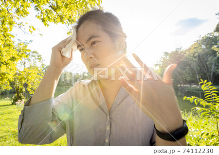 Asian woman wiping sweat on face with tissue paper suffer from sunburn very hot in summer weather problem feel faint, tired female people with heat stroke,high temperature on sunny day,global warming 74112230