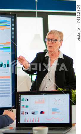 Elderly project manager pointing at desktop presenting statistical data, Elderly project manager pointing at desktop presenting statistical data, 74112324