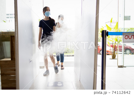 Asian people wear face masks,walk in the automatic disinfection tunnel for disinfecting at gate check point for COVID-19,measures to prevent,make clean and hygienic,new normal life under Coronavirus Asian people wear face masks,walk in the automatic disinfection tunnel for disinfecting at gate check point for COVID-19,measures to prevent,make clean and hygienic,new normal life under Coronavirus 74112642