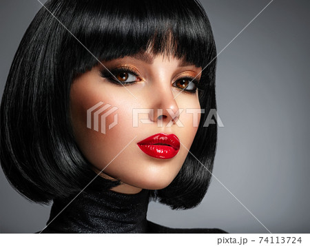 Beautiful brunette girl with red lips and black bob hairstyle. Pretty young woman with black hair. Closeup portrait of a model with bright makeup on a face. Fashion portrait of a pretty lady. 74113724