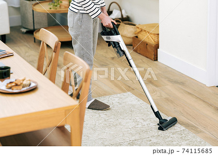 自宅のリビングで掃除機をかける女性 74115685
