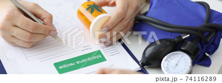Doctor's hands hold can of marijuana and write prescription 74116289