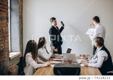 Male speaker giving presentation in hall at workshop. Audience or conference hall. Participants, co-workers listening at the table. 74118213