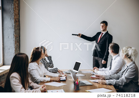 Male speaker giving presentation in hall at workshop. Audience or conference hall. Participants, co-workers listening at the table. 74118218