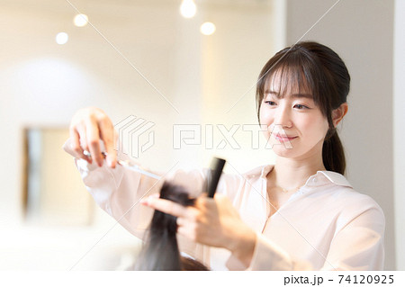 お客の髪を切るヘアスタイリスト 74120925