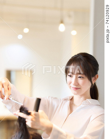 お客の髪を切るヘアスタイリスト 74120929