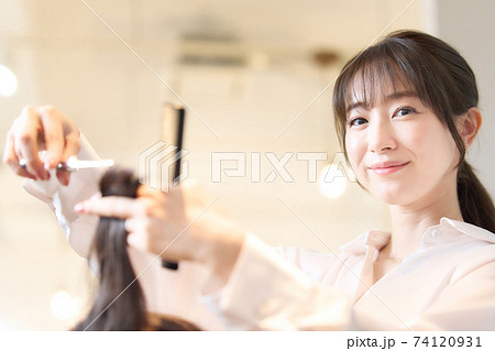 お客の髪を切るヘアスタイリスト 74120931