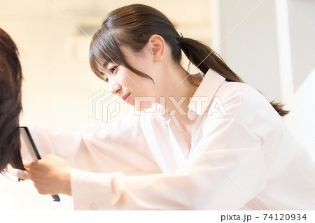 お客の髪を切るヘアスタイリスト 74120934