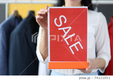 Woman holding plate with inscription sale in clothing store closeup Woman holding plate with inscription sale in clothing store closeup 74121051