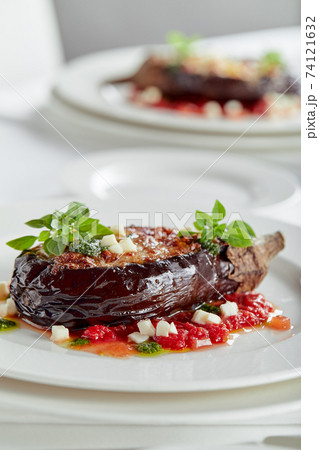 Half baked eggplants with meat, cheese and tomatoes on white background. Banquet festive dishes. Gourmet restaurant menu. White background. Half baked eggplants with meat, cheese and tomatoes on white background. Banquet festive dishes. Gourmet restaurant menu. White background. 74121632