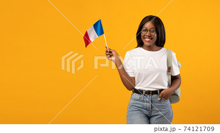 Positive black woman student with backpack holding french flag Positive black woman student with backpack holding french flag 74121709