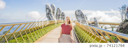 Young woman tourist at Famous tourist attraction - Golden bridge at the top of the Ba Na Hills, Vietnam BANNER, LONG FORMAT 74121766