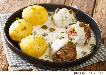 Tasty German Konigsberger Klopse meatballs in caper sauce served with boiled potatoes close-up in a plate. horizontal Tasty German Konigsberger Klopse meatballs in caper sauce served with boiled potatoes close-up in a plate. horizontal 74123514