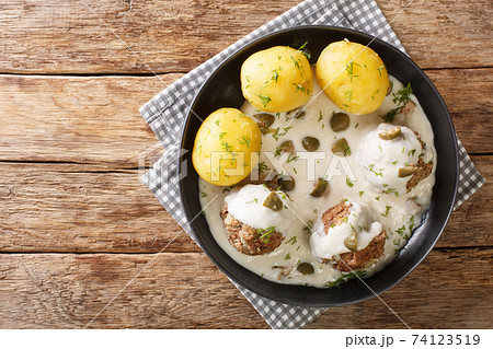 Delicious German meatballs in caper sauce served with boiled potatoes close-up in a plate. horizontal top view 74123519