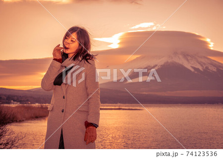 《山中湖》平野の浜から夕焼けの富士山を満喫する女性 74123536
