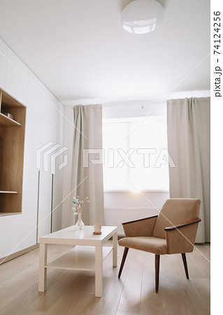 Stylish bright living room with comfortable armchair and table by the window. Stylish bright living room with comfortable armchair and table by the window. 74124256