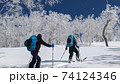 晴天に映える霧氷の木々と雪山をハイクアップする山スキーヤー 74124346