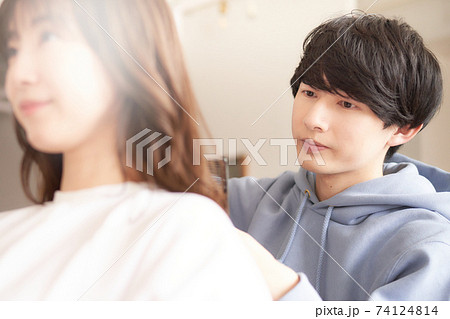 女性の髪をカットをするヘアスタイリスト 74124814