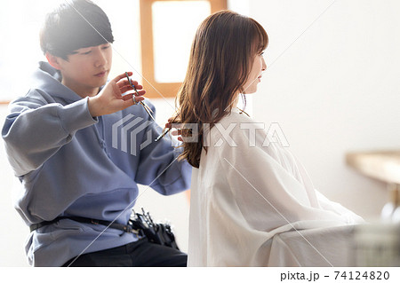 ヘアカットをする美容師と女性客 74124820