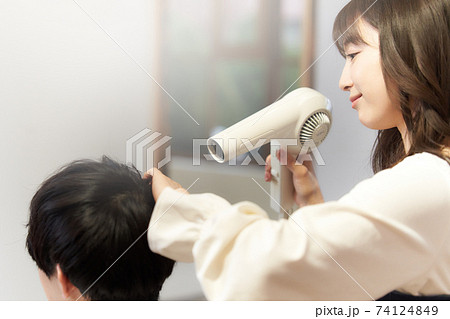 ドライヤーをあてる女性ヘアスタイリストと男性客 74124849