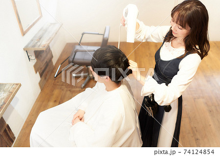 ドライヤーをあてる女性ヘアスタイリストと男性客 ドライヤーをあてる女性ヘアスタイリストと男性客 74124854