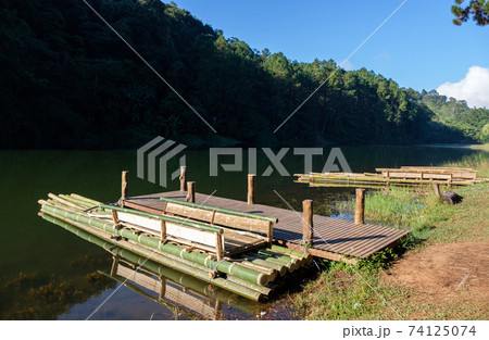 The bamboo raft is floating near the wooden pier. The bamboo raft is floating near the wooden pier. 74125074