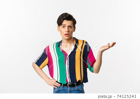 Confused gay man asking what happened, raising hand aside and looking puzzled at camera, standing over white background Confused gay man asking what happened, raising hand aside and looking puzzled at camera, standing over white background 74125241