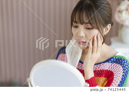 Young woman worrying about rough skin due to mask toothache Young woman worrying about rough skin due to mask toothache 74125445