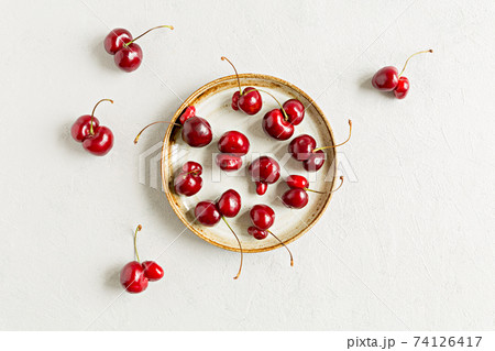 Ugly red berry cherries flat lay on white background on plate. Trendy shaped food. Imperfect, deformation organic berries. Zero waste concept Ugly red berry cherries flat lay on white background on plate. Trendy shaped food. Imperfect, deformation organic berries. Zero waste concept 74126417