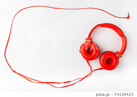 Red round headphones with a cord forming a frame flat lay on a white background with a copy space Red round headphones with a cord forming a frame flat lay on a white background with a copy space 74126425