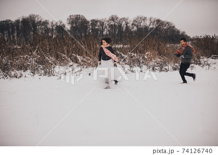 wedding couple running lying in snow laughing having fun playing snowballs wedding couple running lying in snow laughing having fun playing snowballs 74126740