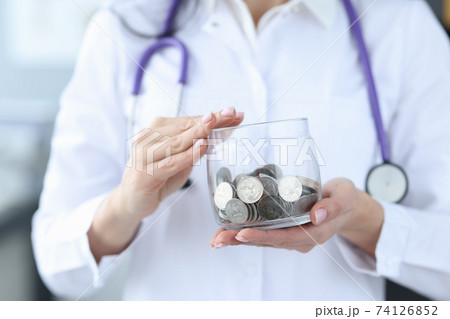 Doctor holding glass jar with coins closeup 74126852