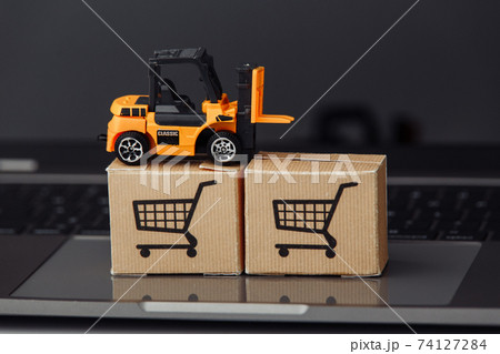 Forklift model on carton boxes on a laptop close-up. Courier services and delivery concept Forklift model on carton boxes on a laptop close-up. Courier services and delivery concept 74127284