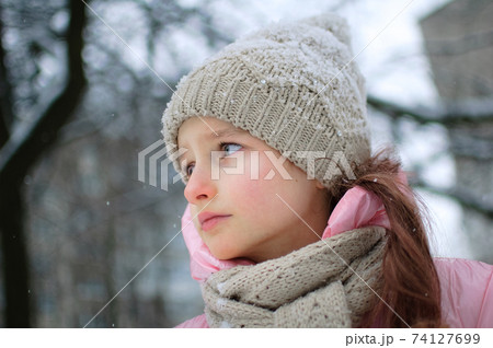 Sad child girl in warm knitted winter clothes spent time outdoors and got frozen. 74127699