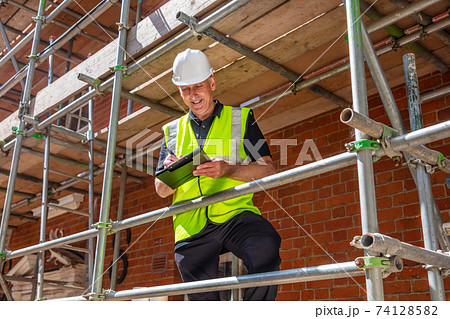 Male Builder Construction Worker Contractor on Building Site With Clipboard Male Builder Construction Worker Contractor on Building Site With Clipboard 74128582