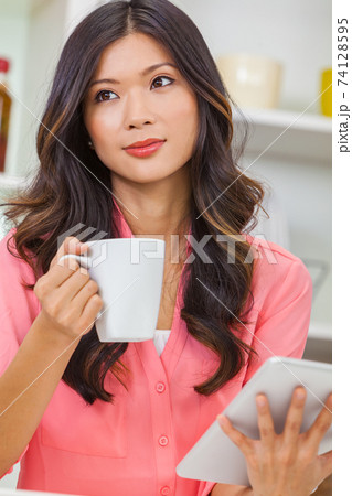 Asian Chinese Woman Using Tablet Computer Drinking Coffee or Tea 74128595