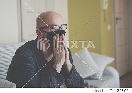 Depressed mature man sitting on a sofa with a face mask on. He experienced bankruptcy. Depressed mature man sitting on a sofa with a face mask on. He experienced bankruptcy. 74129366