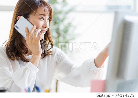 デスクワーク中にスマホで通話している女性 74134575
