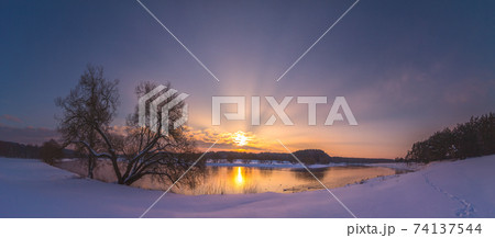 Winter evening landscape with sunrays in the sunset light Winter evening landscape with sunrays in the sunset light 74137544