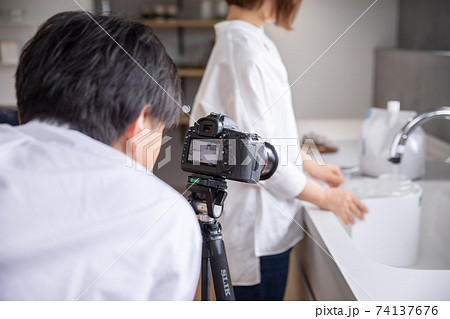 男性カメラマンがキッチンで立っている女性を撮影をしている　photographer 74137676