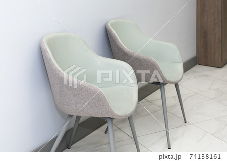 Front view of modern, simple chairs against grey wall in a minimal style, waiting room interior. Chairs in waiting room of doctor's office 74138161
