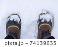 Top view of anonymous traveler in warm boots standing on white snow on winter day. 74139635