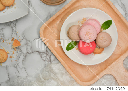 Marble dinning table with a plate of French colourful macarons and biscuit plate 74142360