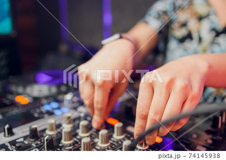 DJ's hand over the laptop and mixing console controlling the sound settings. DJ's hand over the laptop and mixing console controlling the sound settings. 74145938