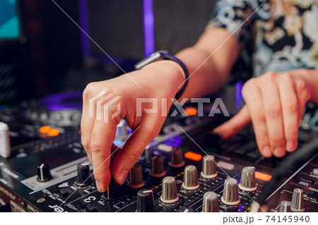 DJ's hand over the laptop and mixing console controlling the sound settings. DJ's hand over the laptop and mixing console controlling the sound settings. 74145940